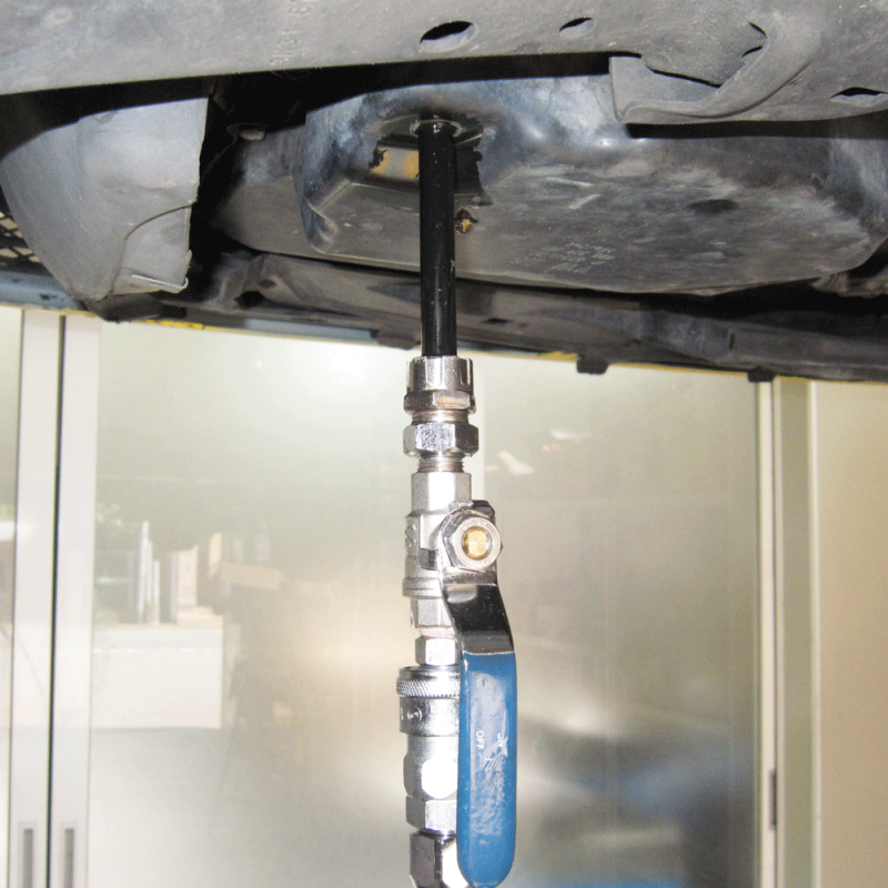 ③施工車両のオイルパンドレーンにアタッチメントを接続し、本体のハンドルを上下に動かしフルードを注入していきます。